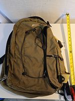 Front view of MEC brown backpack with bungee cord and visible zipper fraying