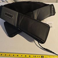 Front view of Medcursor neck and shoulder massager showing ergonomic shape and corded power connection with fabric and leatherette materials