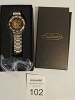 Men's mechanical wristwatch in original black box with foam insert and separate plastic bag with additional band links or packaging.