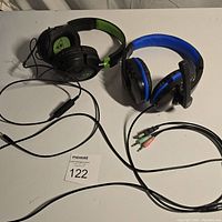 Pair of wired gaming headsets with cables and dual 3.5mm connectors on a white surface.