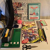 Lot overview including colouring books, sketchbook, pens, pencils, calculator, scissors and other items.