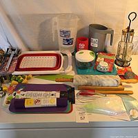 Photo shows assortment of kitchen tools including measuring jugs, strainer, rolling pins, knives, spatulas, whisk, oil dispenser bottles and containers.