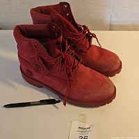 Front/side perspective of red suede Timberland boots with visible scuffs on toe area.