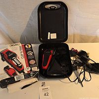 Full view of Wahl Clip And Trim hair clipper, clipper guards, power cords and hard plastic carrying case, with original cardboard box worn and torn, and the clipper inside the opened case.