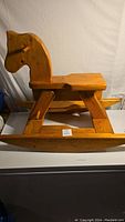 Side view of the wooden rocking horse showing the horse-shaped backrest and curved rockers.