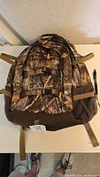 Front view of camo backpack with multiple compartments and adjustable straps.