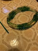 Top-down photo showing the full oval crystal platter with green leaf-like accents circled around the rim.