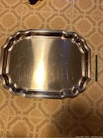 Top view of the large rectangular silver platter with scalloped edges showing surface scratches.