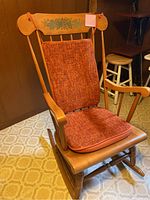 Full view of wooden rocking chair with orange textured cushions on seat and backrest.
