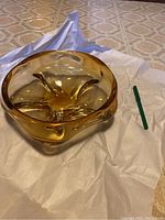 Top angle view showing the full amber glass bowl with sculpted inward curves and thick base.