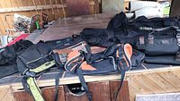 Overview of nine men's suitcases and duffel bags arranged on a wooden table with outdoor background