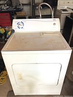 Front view of Inglis white full size dryer showing control panel with cycle dial and start button; surface has noticeable scratches and dirt marks.