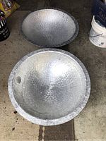 Two large hammered aluminum bowls on the floor showing their size and hammered texture.