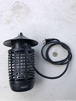 Front view of black Gravitti mosquito bug zapper with power cord and separate bulb on white surface.