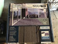 Close-up image of one box showing product label and sample tiles with wood-like surface texture, dimension details, and branding.