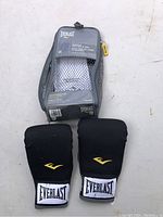 Photo of the packaging pouch with the Everlast neoprene gloves placed below it showing front view and brand logo.