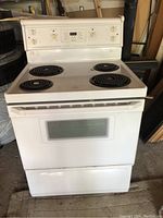 Front view of white full size electric stove and oven with four coil burners and white control panel.