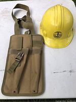 Yellow construction hard hat with tool bag sachet placed on a white table.