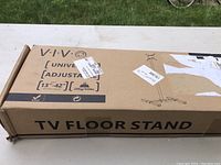 Photo of the Vivo TV floor stand box showing brand, size compatibility (13-42 inch), adjustable universal mount, and weight capacity (20 kg/44 lbs).