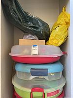 Stacked plastic storage containers and large bags holding wreaths and holiday decoration items