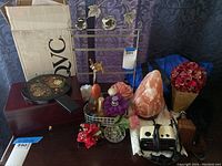 Photo showing the various items on a dark wooden surface including the jewelry box, salt purifier, floral mirror, and assorted holders.