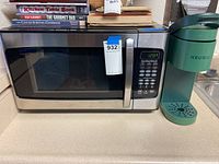 Keurig coffee maker and Hamilton Beach microwave side by side on kitchen counter with books on top of microwave.