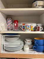 Shelves with assorted plates, mugs, cups, and kitchen items.