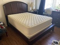 Front and full view of queen wood bed frame with mattress in bedroom.