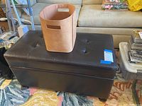 Leather magazine holder placed on top of the vinyl ottoman, showing material and color