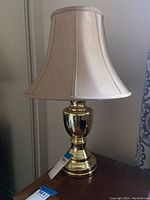 Full view of brass colored table lamp with beige shade