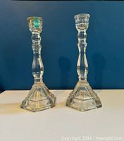 Pair of clear glass Tiffany candlesticks against blue background