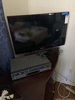 Samsung flat screen TV on swivel base with DVD/VHS combo player below. Power cord visible for DVD/VHS unit.