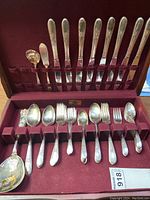 Flatware set laid out inside original wood box showing knives, forks, spoons, salad forks, and serving pieces.