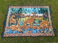Full view of the rectangular vintage Italian tapestry laid flat on grass, showing detailed deer scene and ornate border.
