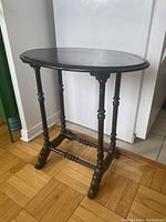 Side angled view of the wooden console table showing the oval top, turned legs and the cross stretcher base with curved feet.