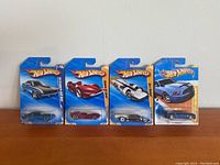 Four Hot Wheels 1:64 scale model cars in original blister packaging arranged side by side showing front view.