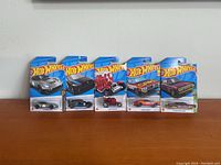 Five Hot Wheels 2021 mainline series cars in original packaging lined up on a white background.