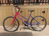 Side view of purple and red Leader mountain bike showing left side including pedals, chain, and frame