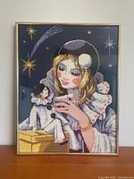 Full frontal photo of the framed needlepoint artwork showing the full design and frame against a plain background.