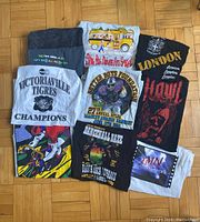 View of all ten folded graphic T-shirts arranged for identification of designs and colors
