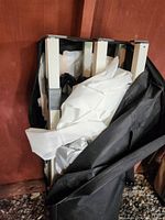 Close up of folded shelter frame and white canopy fabric inside black storage bag.