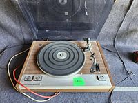 Front view of Craig turntable showing wood grain base, rubber platter mat, and clear hinged dust cover in upright position.
