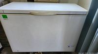 Front view of a white Danby chest freezer with handle and a green lot sticker.