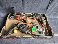 Box containing three electric drills and one vintage jigsaw with cords, showing overall condition