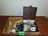 Box containing wood shoe forms, plastic bags with glass eyes and assorted tools and accessories in a brown plastic case