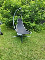 Front view of the hammock chair with visible frayed edges on fabric seat and steel frame structure.