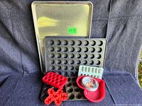 Photo of baking lot including large metal baking sheet, mini cupcake pan, silicone molds and measuring cup.