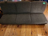 Top view of the brown textured fabric fold down couch with three cushions on seat and backrest on wooden floor.