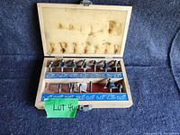 Wooden case with foam lining open showing 14 Mastercraft router bits arranged in two rows inside, case shows stains and wear.