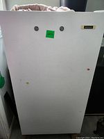 Front view of white Frigidaire upright freezer with minor surface marks and green lot sticker.